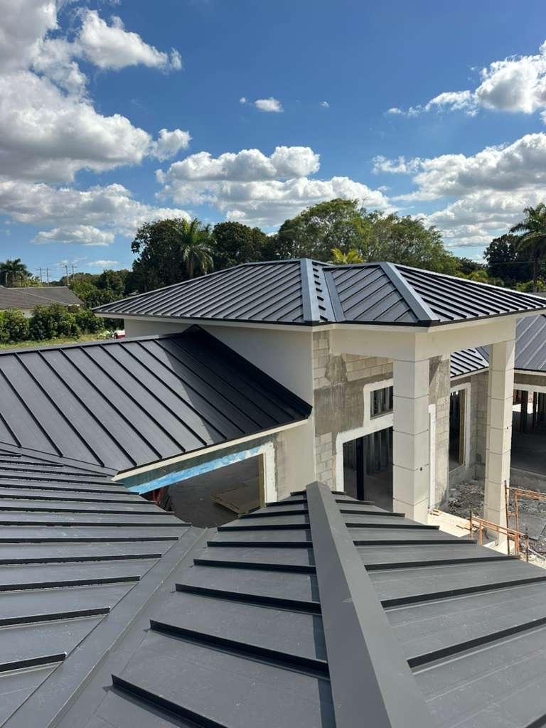 Dark standing-seam metal roof with hip ridge and ridge vent installed by Safetech Roofing and Windows in South Florida