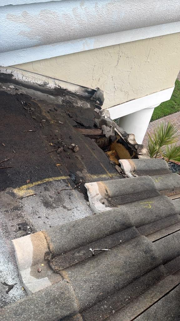 Tiles marked and lifted at the eave to expose failed sealant and flashing on a Florida tile roof