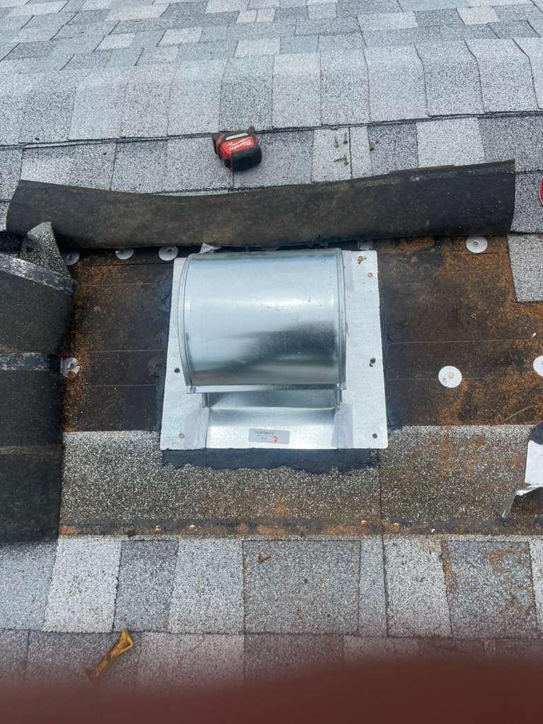 New galvanized goose-neck exhaust vent with integral flashing plate set over a duct penetration on a shingle roof