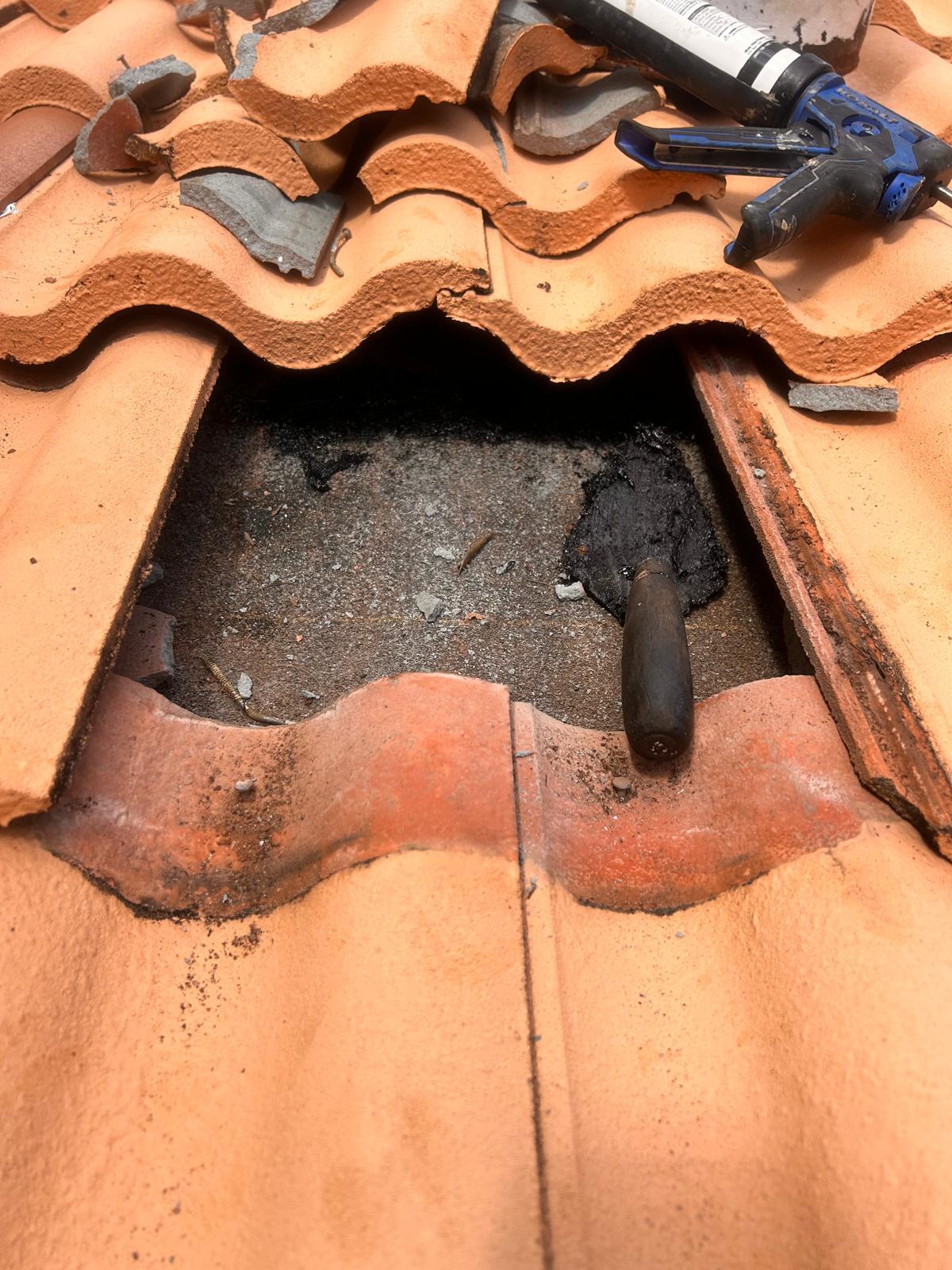 Failed roof underlayment exposed beneath lifted concrete tiles, patched with modified bitumen mastic, on a Broward County tile roof repair