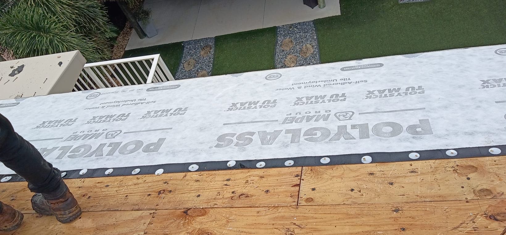 Self-adhered underlayment meeting bare plywood decking, with cap fasteners along the lower edge of the membrane