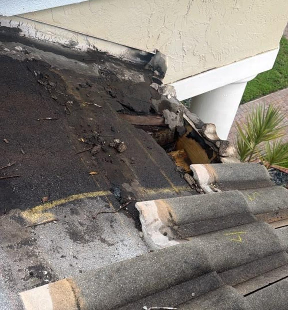 Tile roof eave from outside with the fascia opened up at the tile line and dark failed sealant