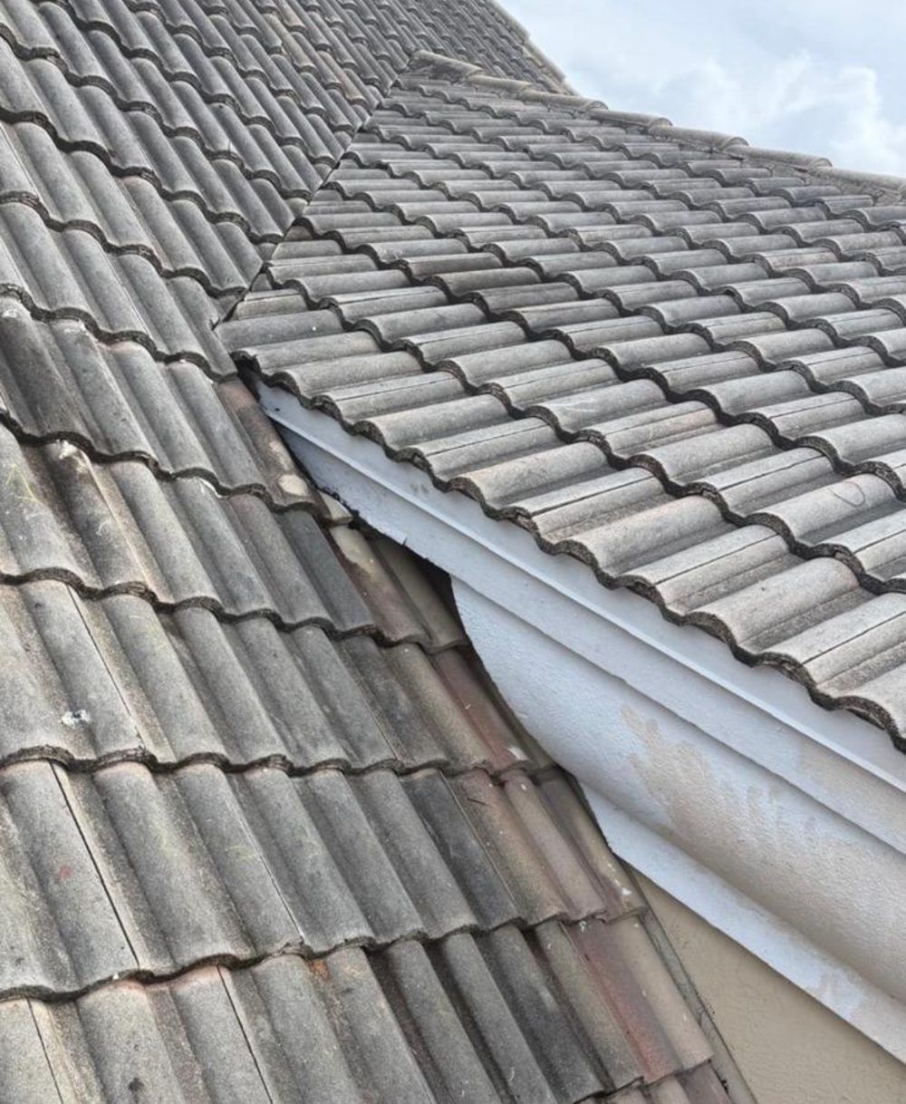 Valley between two tile roof planes with debris and a worn eave termination, during a leak survey