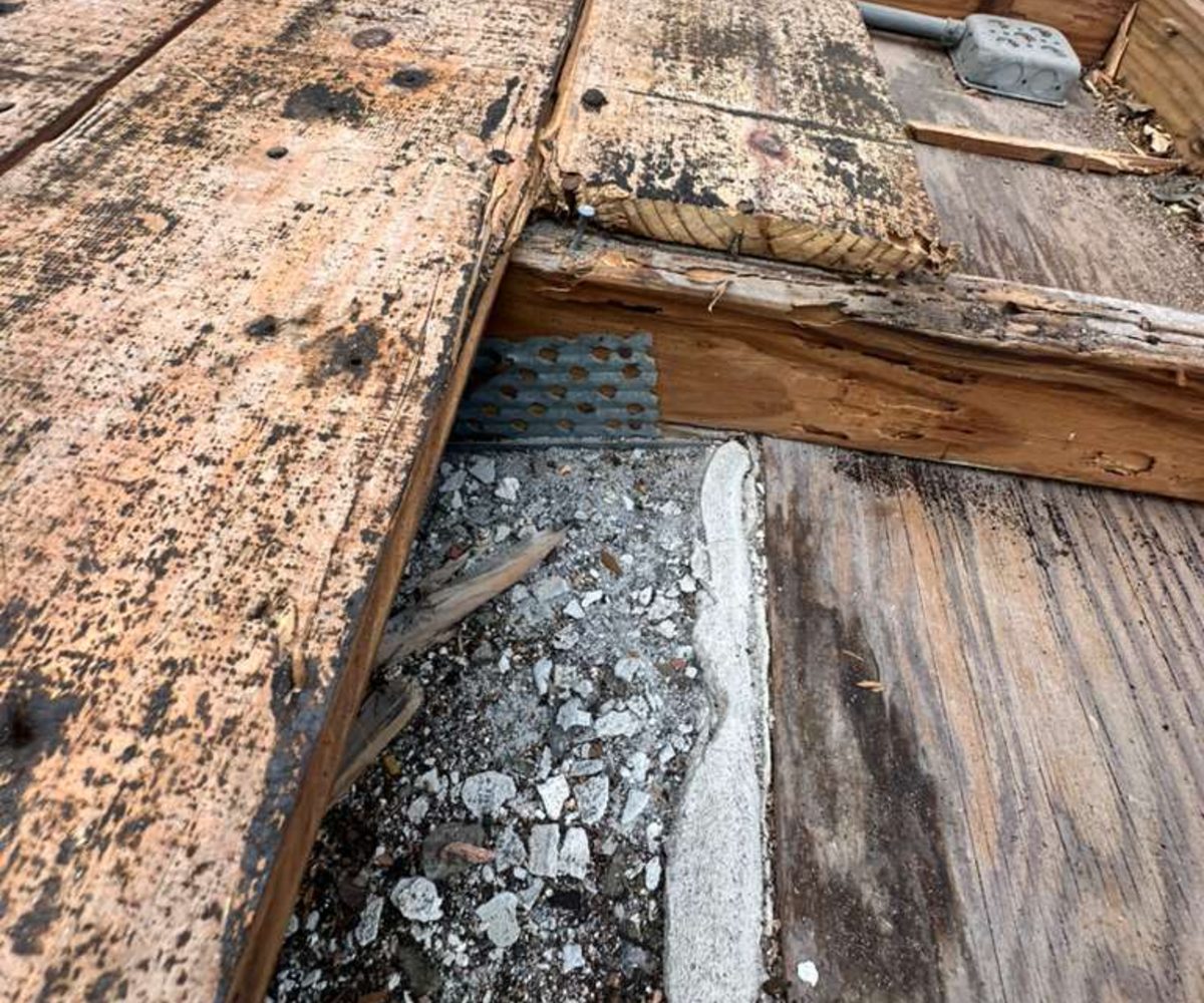 Underside of a roof deck and framing at the wall line where water tracks before it reaches a ceiling