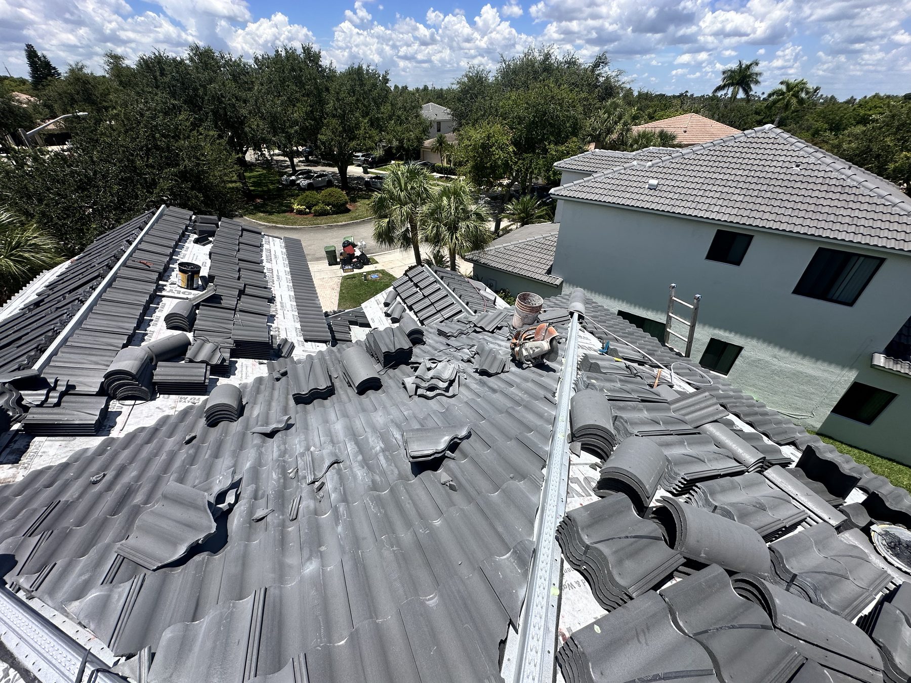 Fresh concrete tiles loaded across the underlayment mid-install on a Broward County tile roof replacement