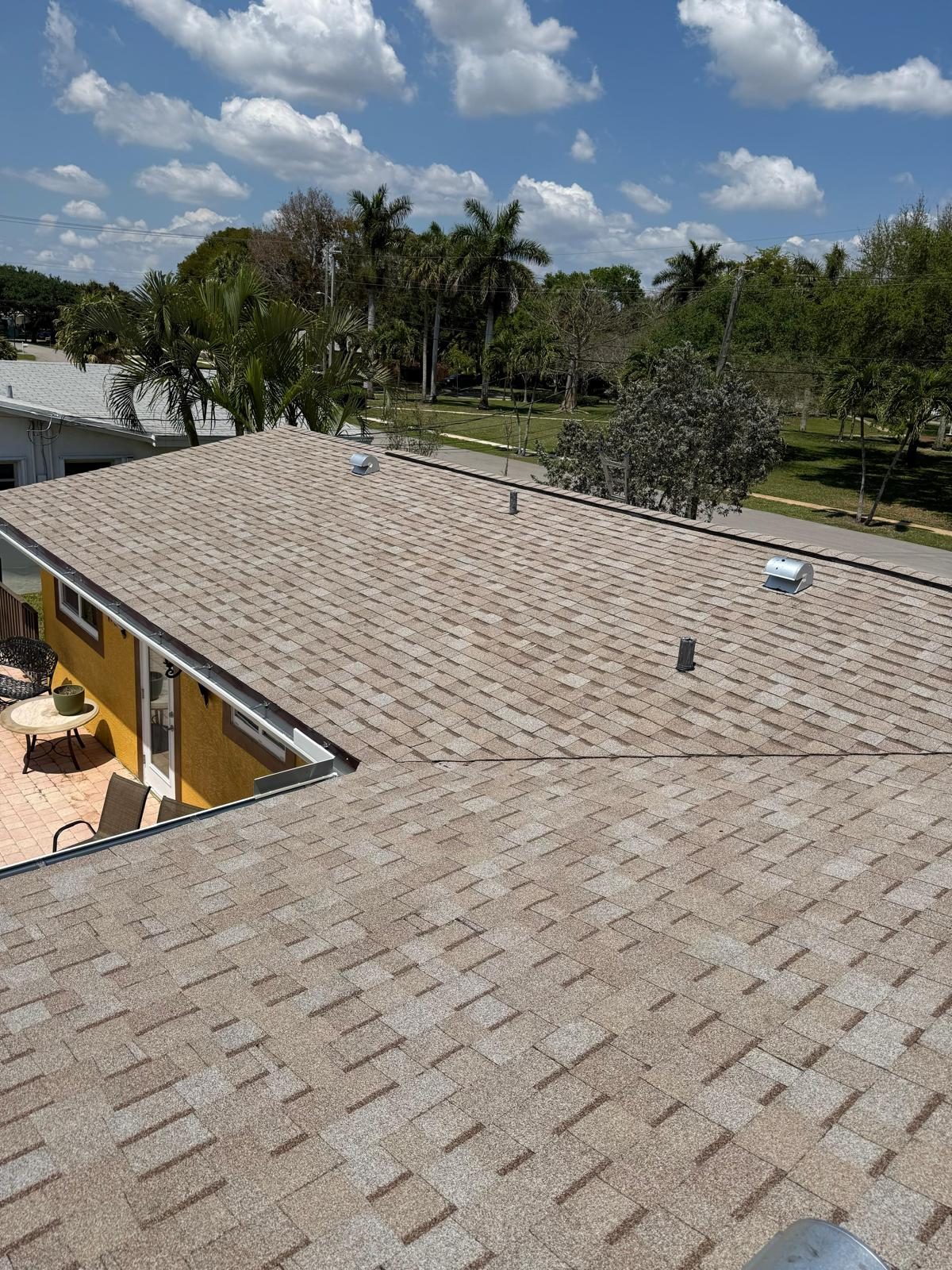 Completed tan architectural shingle roof on a Broward County home seen wide across the front