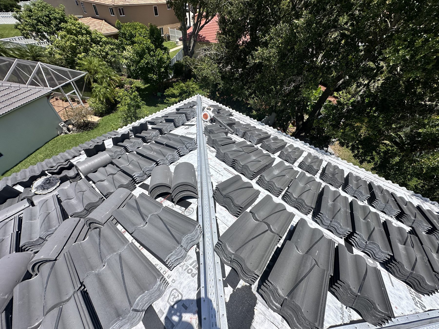 Tiles distributed in stacks across the underlayment ready for install on a Broward tile re-roof