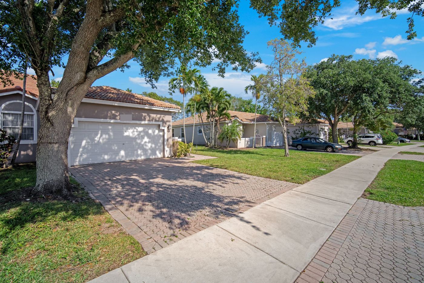 Street of single-story tile-roofed homes under mature oak trees in Fort Lauderdale, Florida