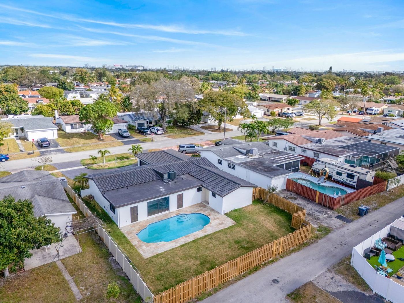 Aerial view of a tile and flat roof home with a pool in a South Florida neighborhood