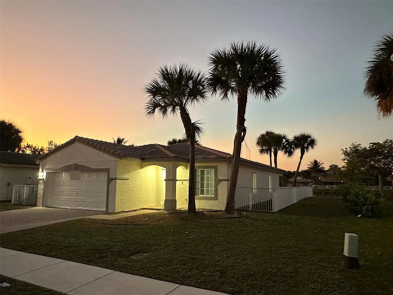 Single-story tile-roofed home with a fenced lakefront yard in Miramar, Florida