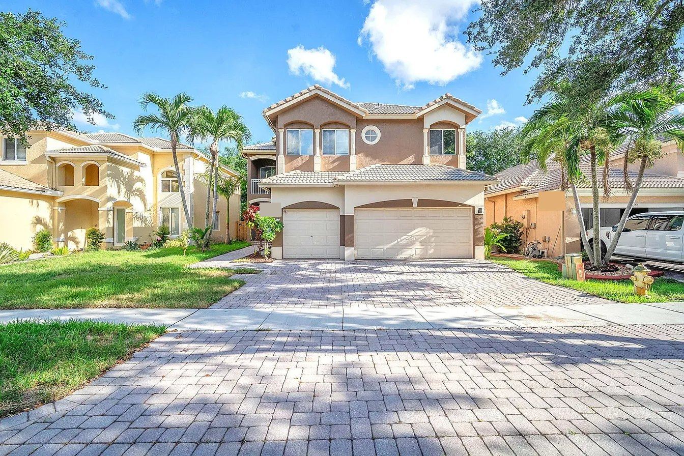 Two-story stucco home with a flat concrete tile roof and three-car garage in Miramar, Florida