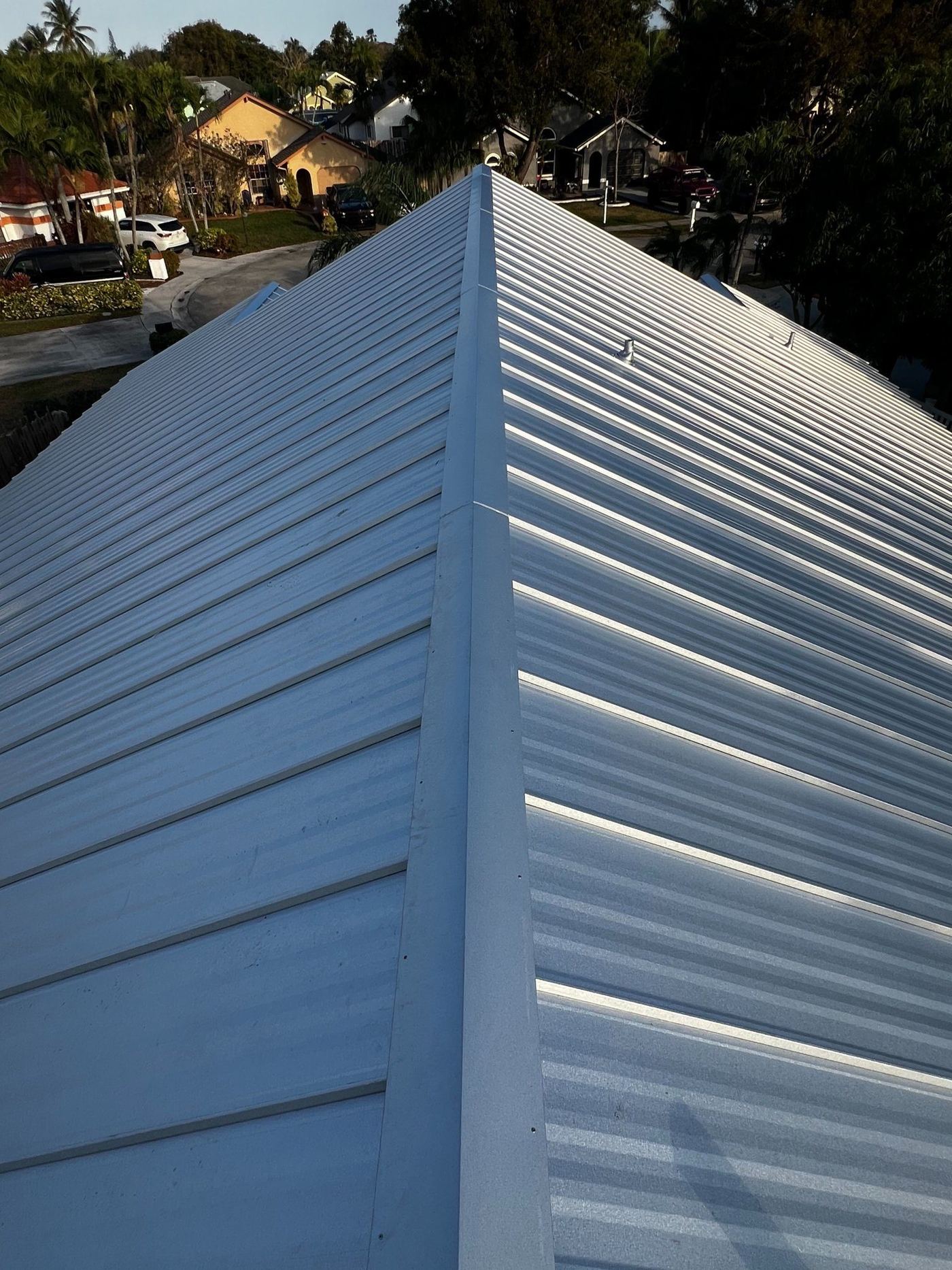 Close view of a metal roof ridge cap and panel seams on a South Florida home