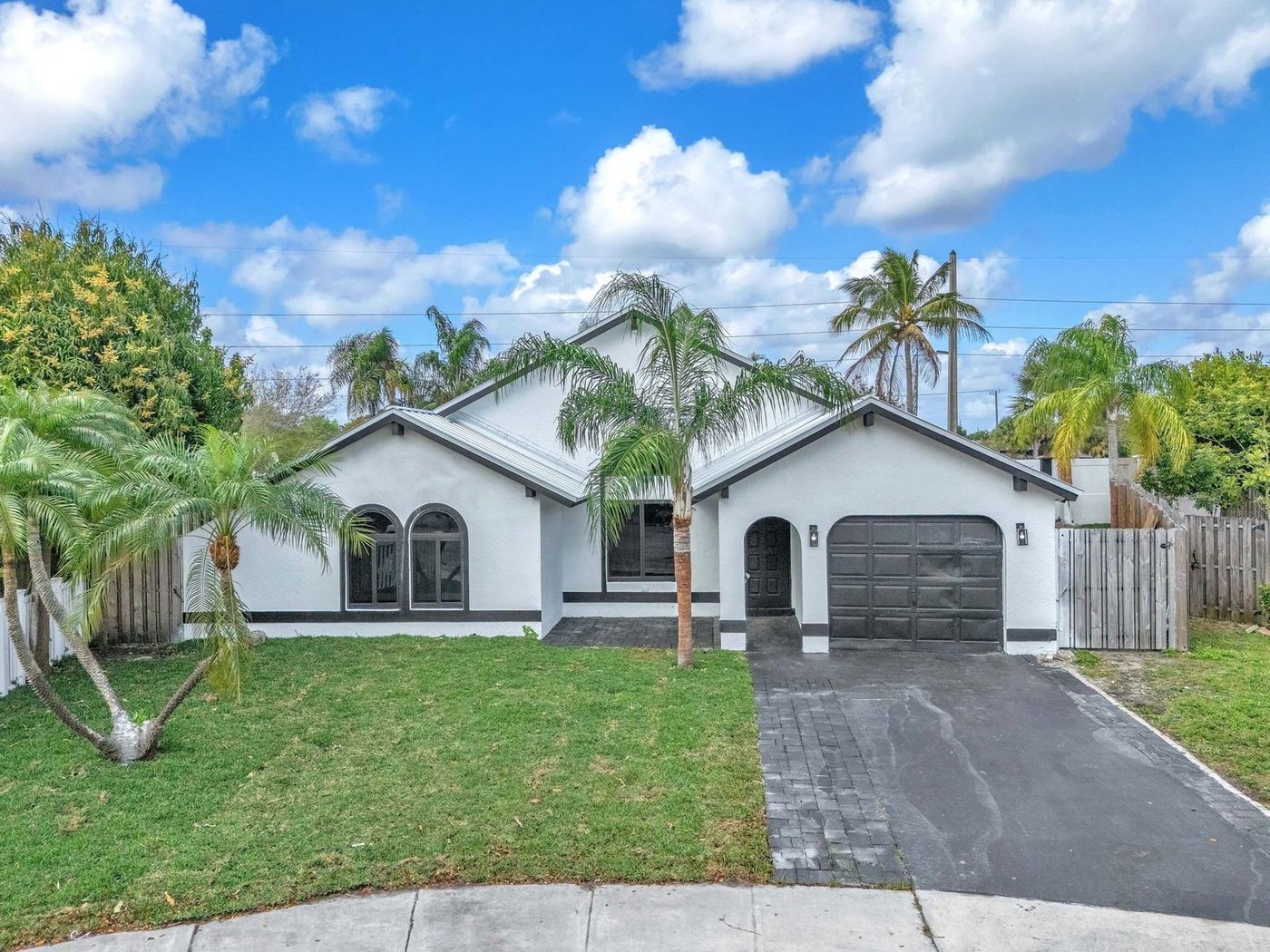 Front elevation of a white home with a metal roof in Sunrise, Florida