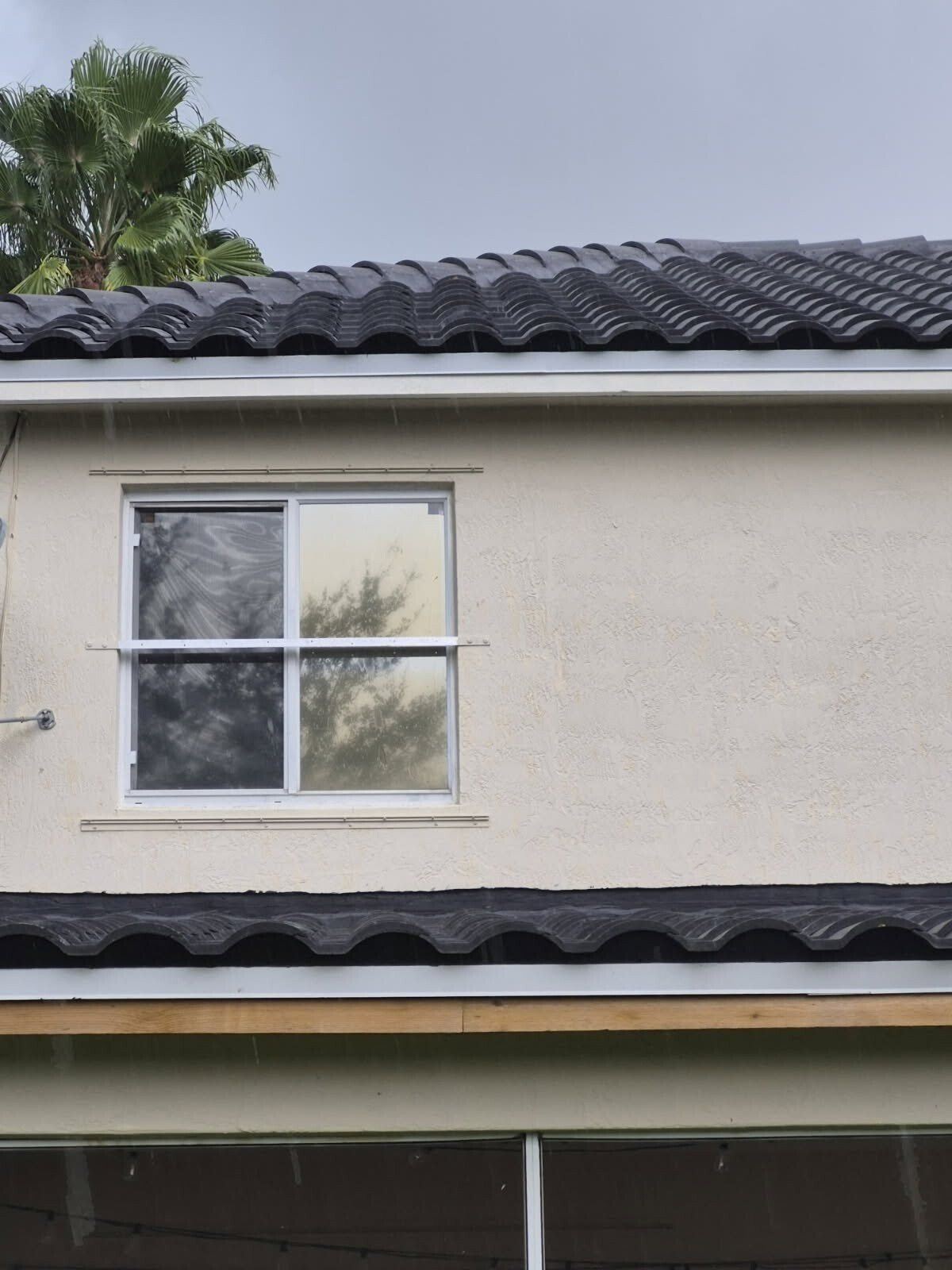 New charcoal barrel tile and drip edge at the lower eave of a Tamarac, Florida home, with new fascia board before paint