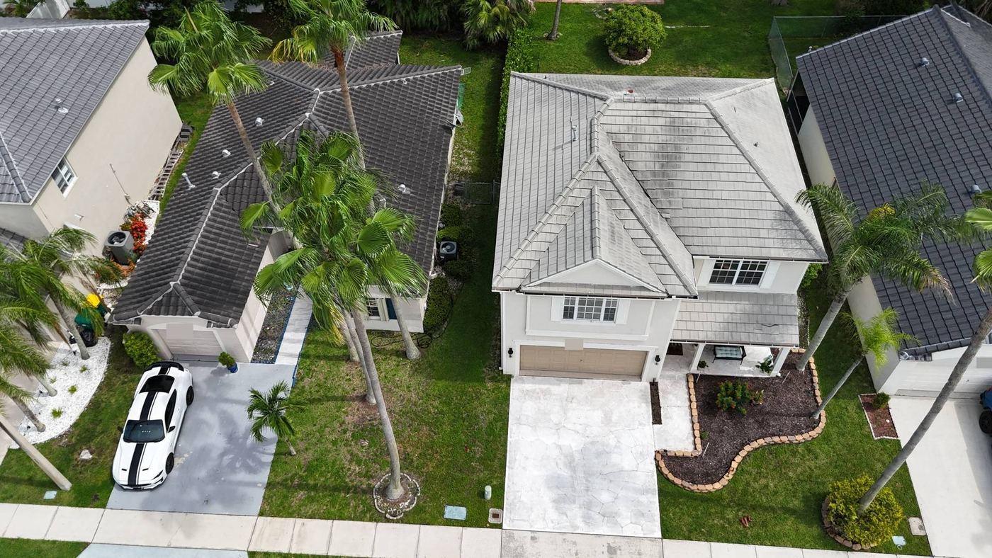 Drone view from above of a Tamarac, Florida home with an older flat concrete tile roof before replacement