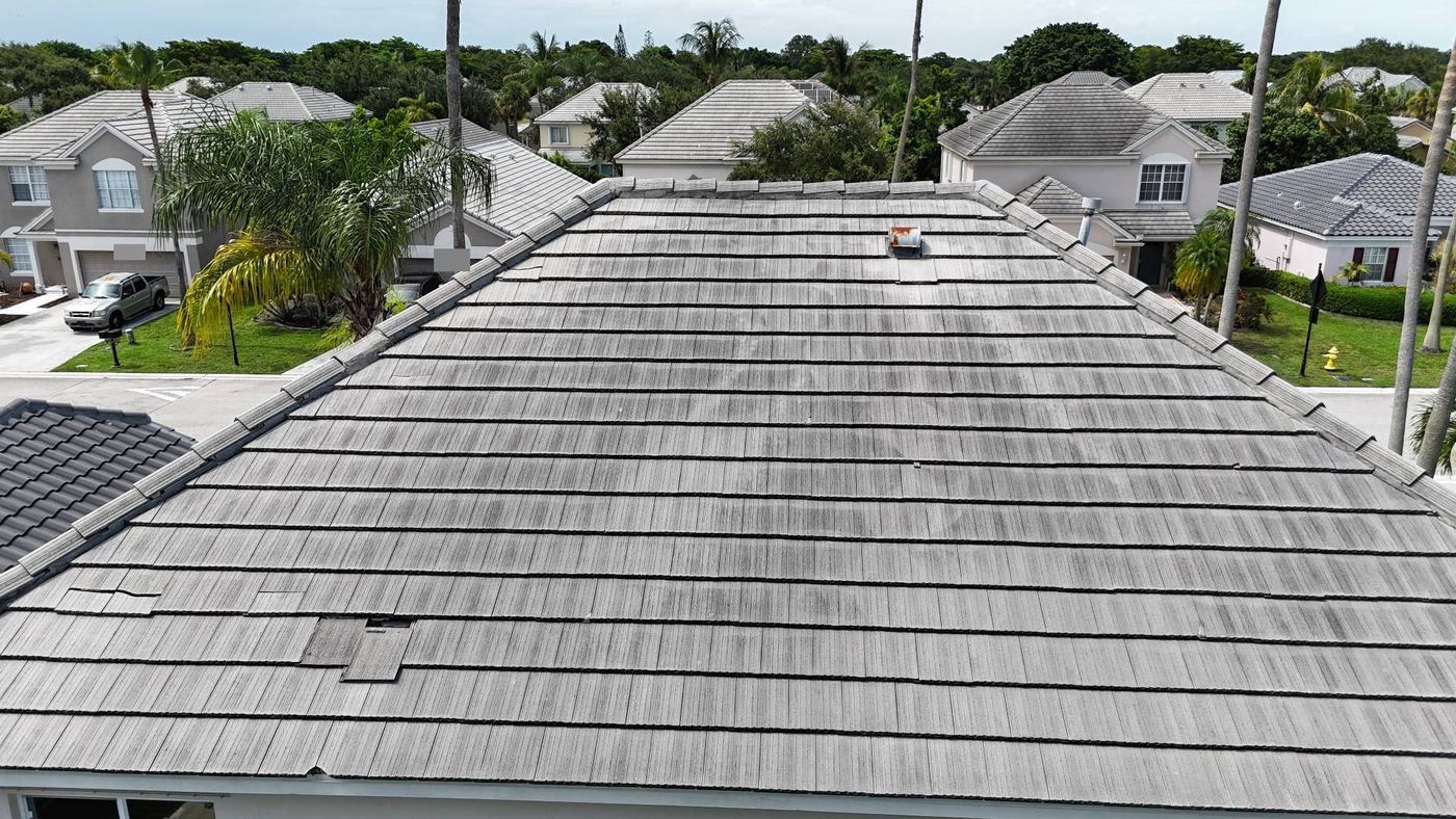 Broken and slipped flat concrete roof tiles and a rusted vent on a Tamarac, Florida roof