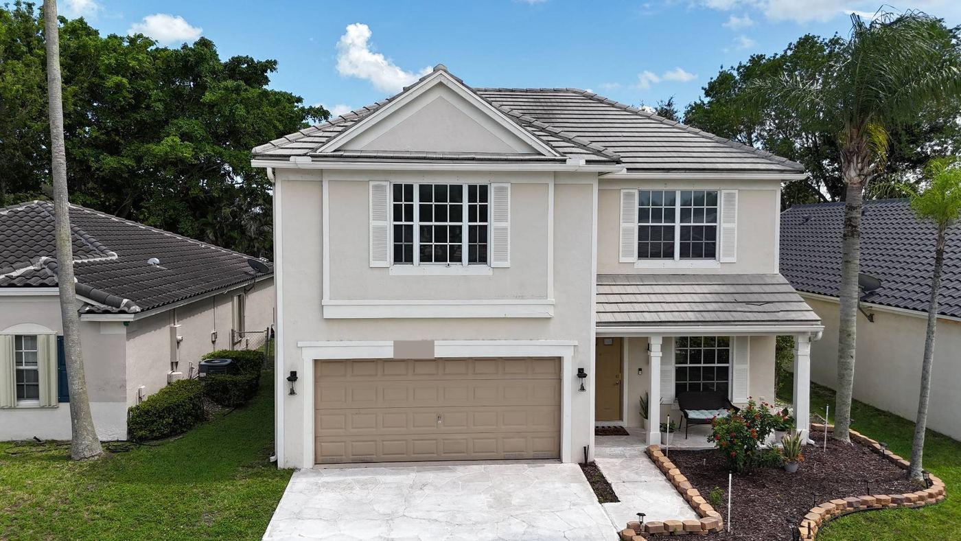 Two-storey Tamarac, Florida home with a weathered flat grey concrete tile roof before replacement